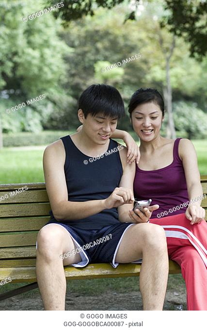 Young couple using an electronic organizer in a park