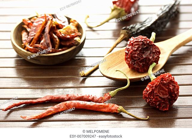 Assortment of dried chili peppers on wooden matt