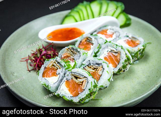 Perfect sushi, traditional Japanese cuisine. Delicious uramaki with sweet and sour sauce on the decorated plate, black background