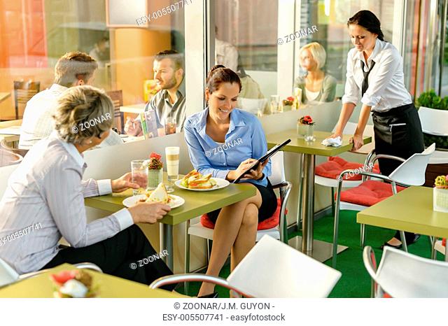 Businesswomen talking business in lunch break cafe