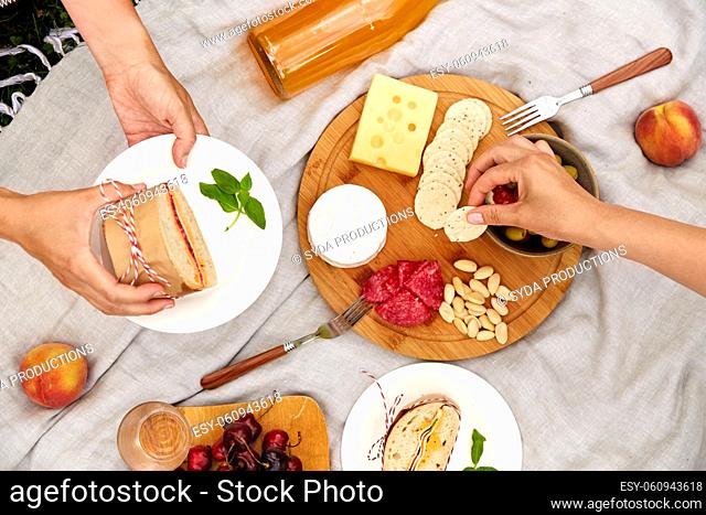 close up of hands with food and drinks on picnic