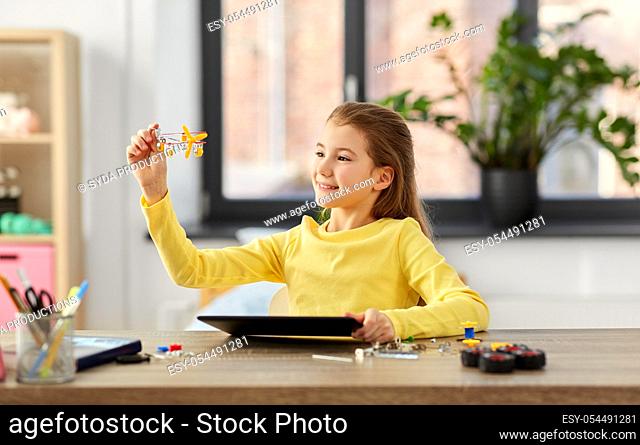 girl with tablet pc and robotics kit at home