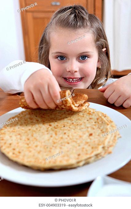 adorable little girl eating crepes