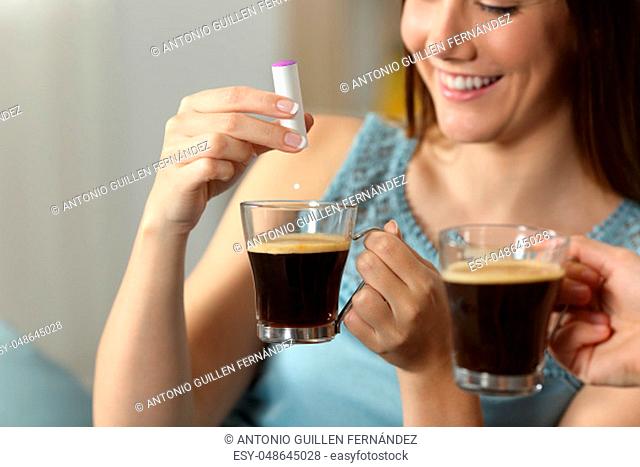 Close up of a woman hand throwing saccharine into a coffee cup sitting on a couch in the living room at home