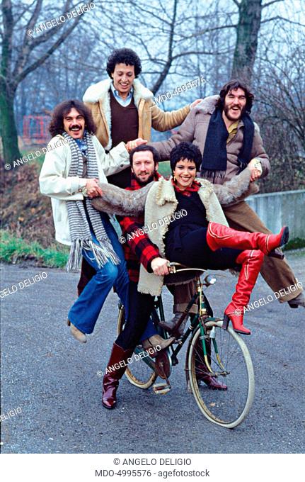 Matia Bazar (Giancarlo Golzi, Aldo Stellita, Antonella Ruggiero, Piero Cassano and Carlo Marrale) posing smiling balancing on a bike. 1978