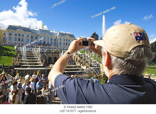 Man taking a photograph of the Grand Cascade in the park of Peterhof Palace, St. Petersburg, Russia