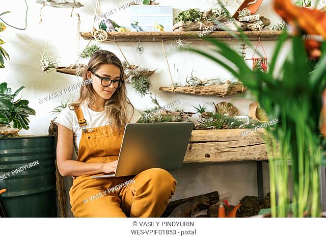 Young woman using laptop in a small gardening shop