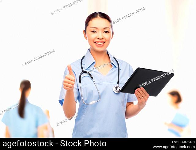 nurse with tablet pc shows thumbs up at hospital