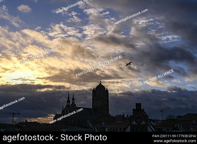 PRODUCTION - 29 December 2022, Mecklenburg-Western Pomerania, Stralsund: The silhouette of St. Jacob's Church and the spire of St