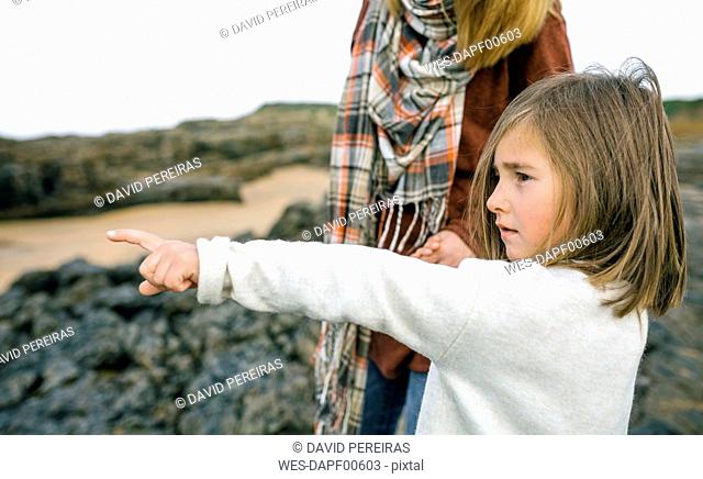 Girl with mother pointing her finger on the beach in winter