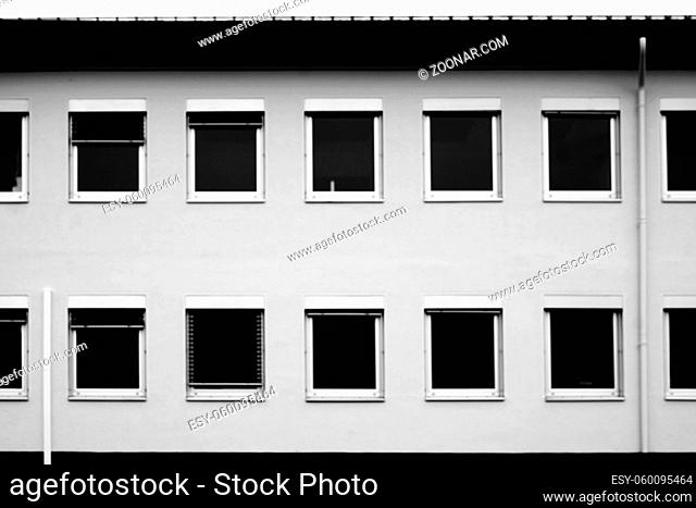 Die einfachen Fenster eines Bürohauses mit schwarzen Jalousien