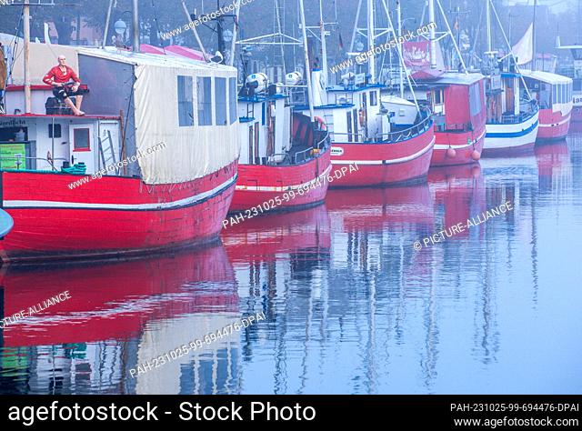 25 October 2023, Mecklenburg-Western Pomerania, Rostock: The red fish boats for sale lie in the fog at the Alter Strom. With fog