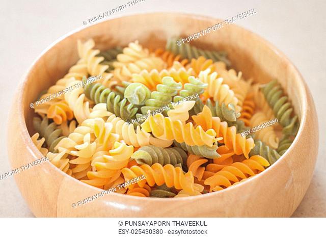 Raw fusilli pasta on wooden bowl, stock photo