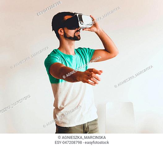 Young bearded man wearing virtual reality. Smartphone using with VR goggles headset