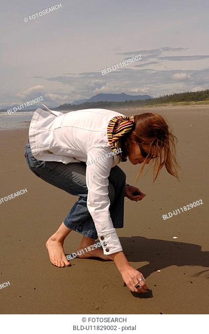 Young girl picking up shells on beach