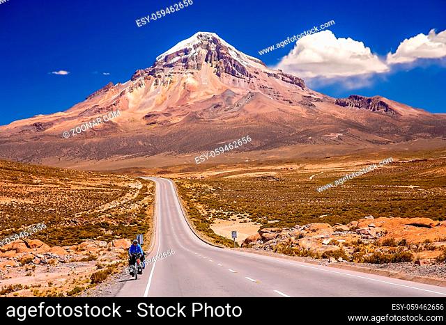 Female solo cyclist riding on bicycle on the beautiful road through Nevado Sajama National Park, Bolivia, South America