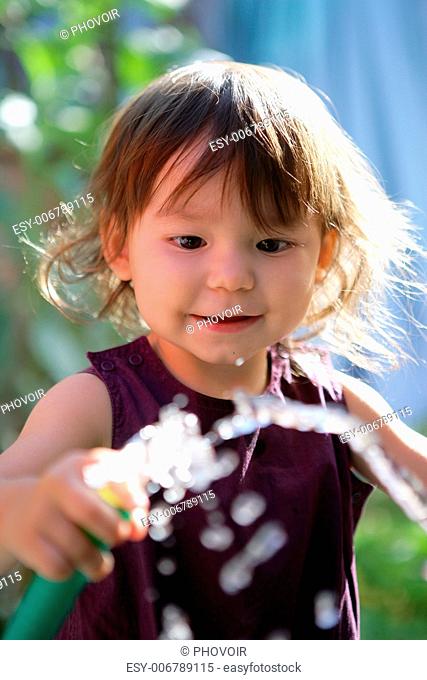 Toddler playing with garden hose