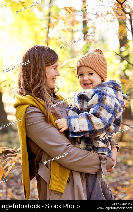 Happy mother carry cute boy in park