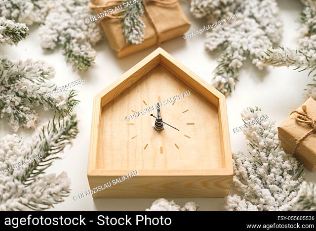 Christmas and New Year still life. Wooden clock shows five minutes to midnight. Fir branches and boxes around