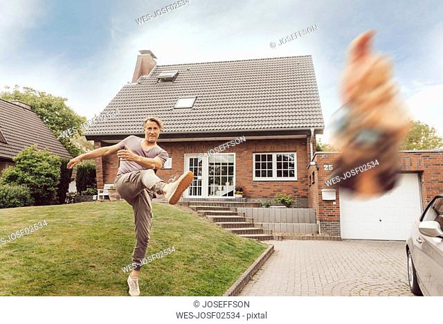 Mature man kicking away garden gnome in front of his home