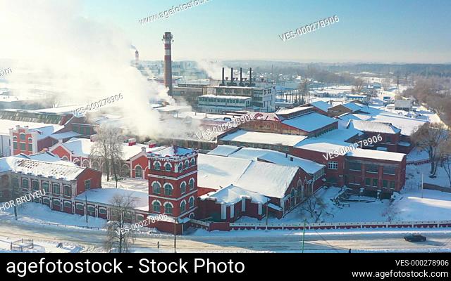 Dobrush, Gomel Region, Belarus. Aerial View Of Old Paper Mill Factory. Bird's-eye View At Sunny Snowy Winter Day 4K. Plant Pipe With Escaping Steam Or Smoke