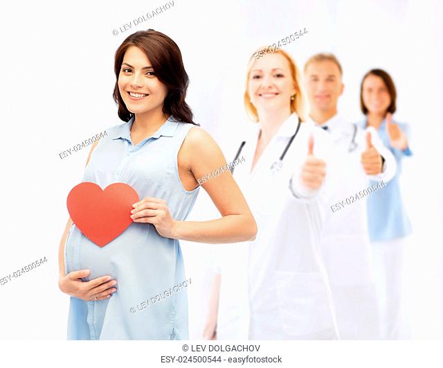 pregnancy, healthcare, medicine, people and expectation concept - happy pregnant woman with red heart shape touching her belly over group of doctors or...