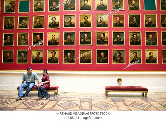 Couple seated in front of portrait gallery of the portrait gallery of the 1812 war heroes in the Hermitage Museum (Winter Palace). St Petersburg
