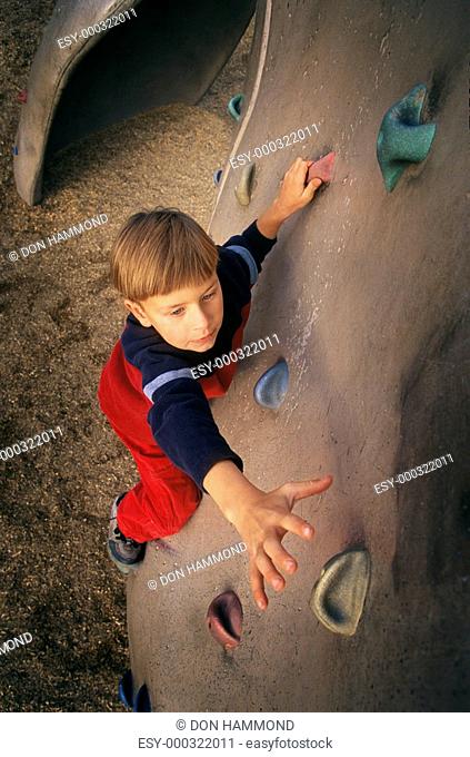 Young boy ascending climbing wall