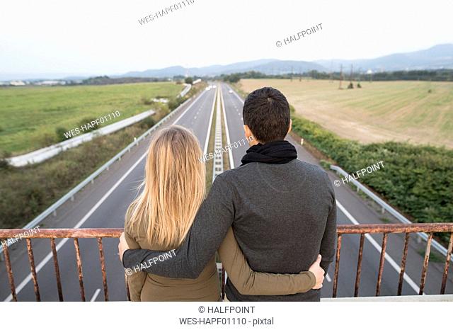 Couple on bridge looking at motorway