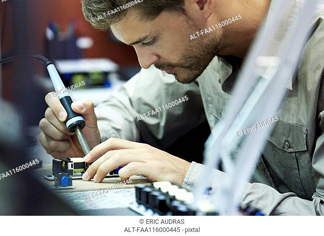 Engineer soldering circuit board in office