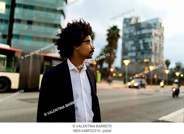 Spain, Barcelona, businessman standing at a street in the city at dusk