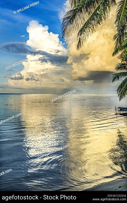 Rain Storm Coming Cloudscape Beach Sunset Palm Trees Reflection Blue Water Moorea Tahiti French Polynesia. Different blue colors in water in lagoon and coral...