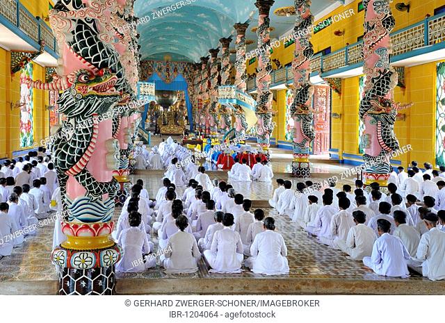 Praying devout men and women, ceremonial midday prayer in the Cao Dai temple, Tay Ninh, Vietnam, Asia