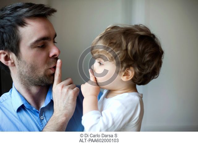 Father teaching toddler son to hush