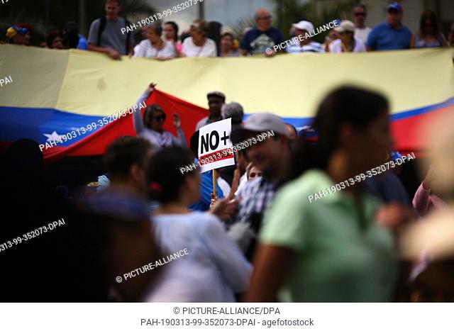 12 March 2019, Venezuela, Caracas: ""No more dictatorship"", is written on the poster of a demonstrator protesting against the lack of electricity and water of...