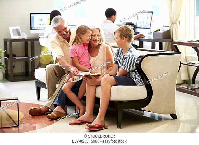 Grandparents With Grandchildren Sitting In Hotel Lobby
