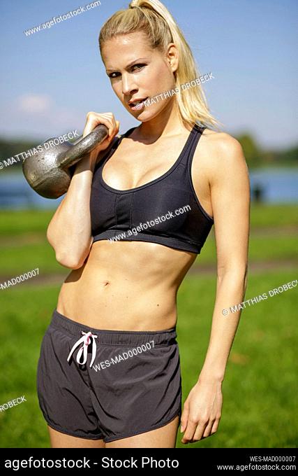 Germany, Young athletic woman with kettlebell
