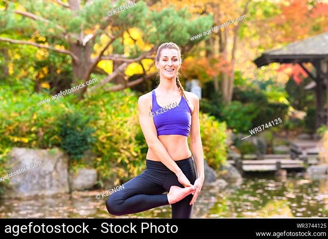 Woman training yoga outdoor in autumn or fall park