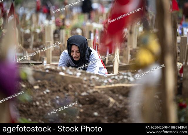 23 April 2023, Turkey, Kahramanmaras: A young woman sits weeping at the grave of her sisters, who died in the earthquake in February