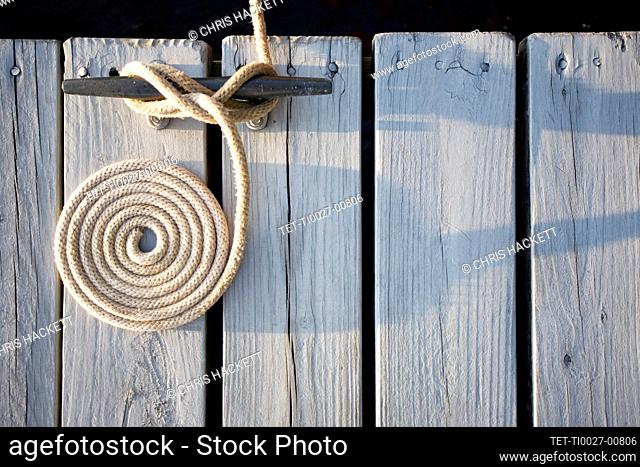 Overhead view of coiled rope tied around bollard