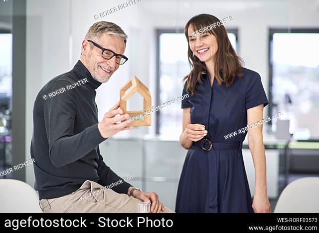 Two smiling architects looking at model house in office