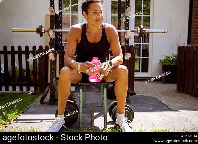 Woman taking a break from weightlifting on sunny patio