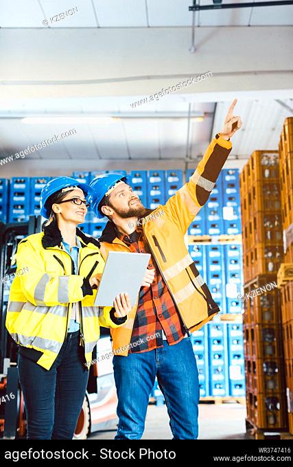 Workers in a logistics warehouse planning the next project using data supplied on a tablet computer