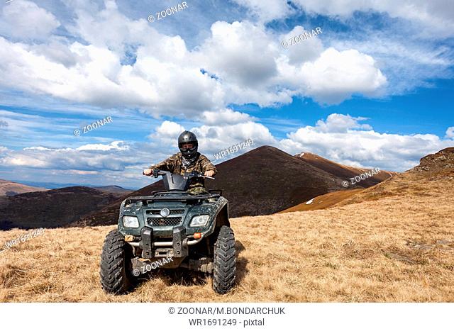 male rider sitting on ATV at mountain top