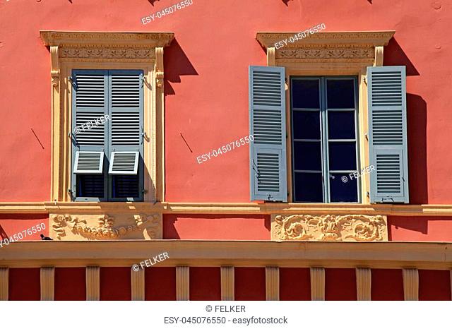 Ornate windows with grey shutters in old red stucco house, Nice, France