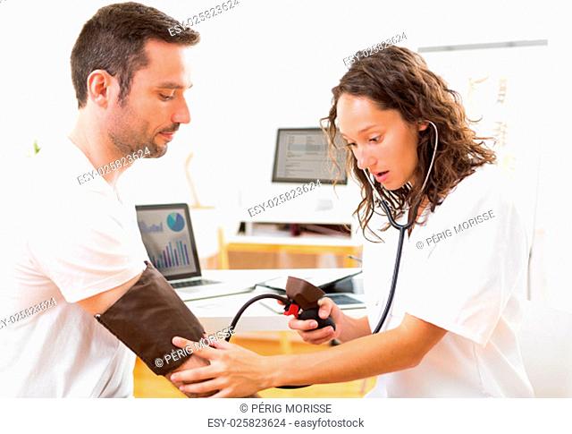 View of a Young attractive doctor checking patient's blood pressure