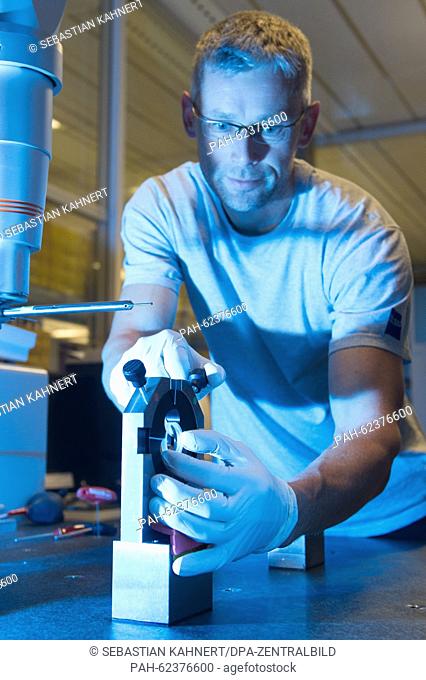 Lutz Wiedemann holds an aspheric lens during the tactile measurement in the department for high performance optics of the Carl Zeiss AG in Jena (Thuringia)