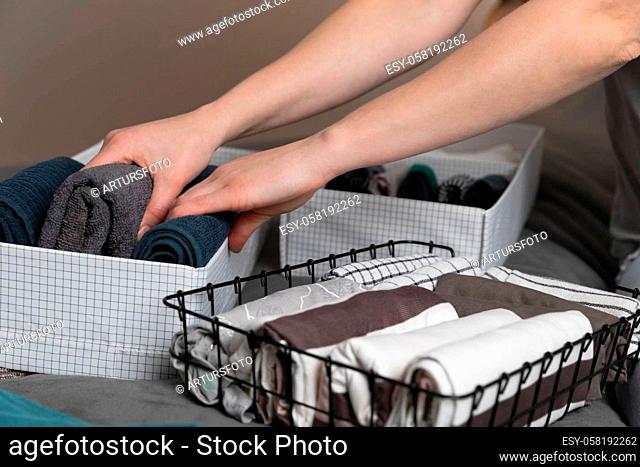 Vertical storage of clothing.Women organize clothes in a modern bedroom. Women sorting clothes in baskets room cleaning concept