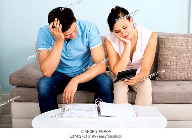 Young Unhappy Couple Calculating Bills At Home