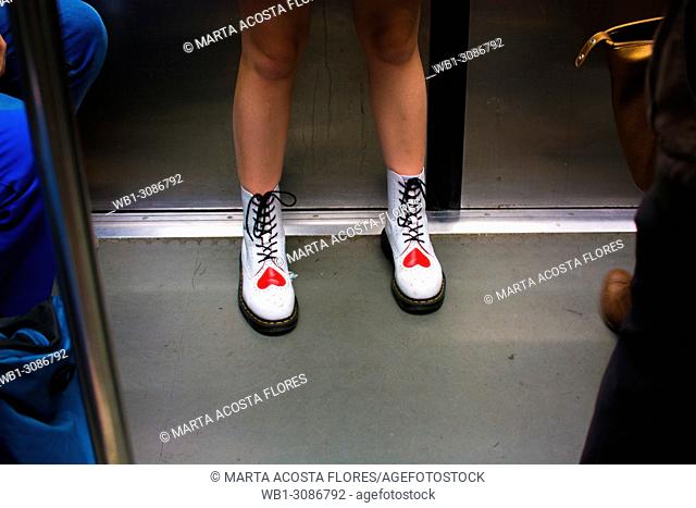 Legs of a girl wearing white boots with a red heart print in the underground of Paris. France